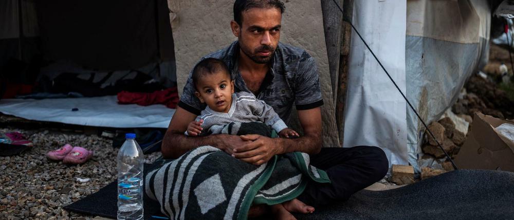 Ein Mann sitzt mit einem Kind vor einer Unterkunft im Flüchtlingslager Moria auf der griechischen Insel Lesbos.