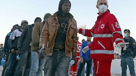 Mitarbeiter des italienischen Roten Kreuzes und gestrandete Flüchtlinge auf Sizilien. 