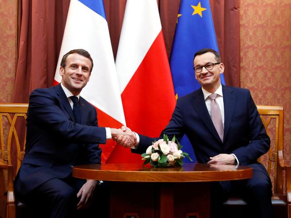 Frankreichs Präsident Macron und Polens Premierminister Morawiecki schütteln am Montag in Warschau die Hände.