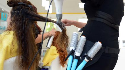 Eine Friseurin föhnt einer Kundin die Haare.