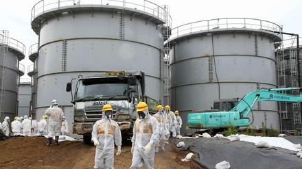Arbeiter in Schutzkleidung vor riesigen tonnenartigen Tanks