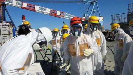 Vor wenigen Tagen hat Industrieminister Tshimitsu Motegi (roter Helm) die havarierten Atomanlagen in Fukushima besucht. Er ließ sich von Mitarbeitern der Betreiberfirma Tepco erklären, warum seit Monaten radioaktiv verseuchtes Wasser in den Pazifik gelangt. Tepco hat das Foto selbst herausgegeben. 