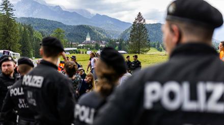 Eine Gruppe von Polizisten in Sichtweite von Schloss Elmau (im Hintergrund) beobachtet eine Demonstration. 