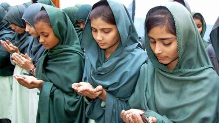 Pakistanische Schulmädchen beten für die Opfer.