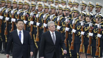Bundespräsident Joachim Gauck and Chinas Präsident Xi Jinping schreiten vor der Großen Halle des Volkes in China die Ehrengarde ab. 