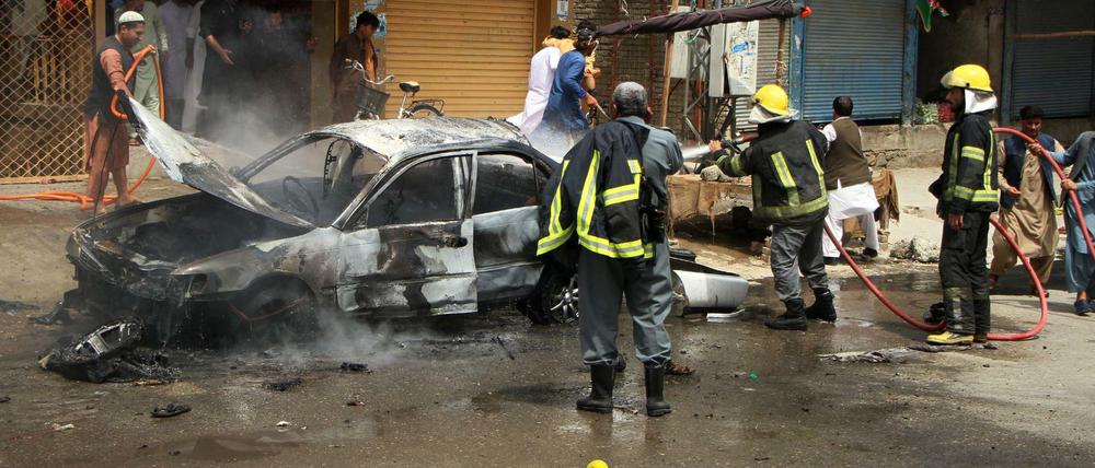 Afghanische Feuerwerkräfte löschen einen Brand an einem Auto nach einer Explosion.