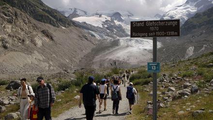 Zahlreiche Wanderer pilgern zum Morteratschgletscher bei Pontresina im Oberengadin (Archivbild vom 22.07.2003) an einem Schild vorbei, dass den Stand der Gletscherzunge aus dem Jahr 1970 markiert. Auf der Suche nach Abkühlung spazieren sie von der Station Morteratsch zum Fuße des Morteratschgletschers im Berninagebiet. 