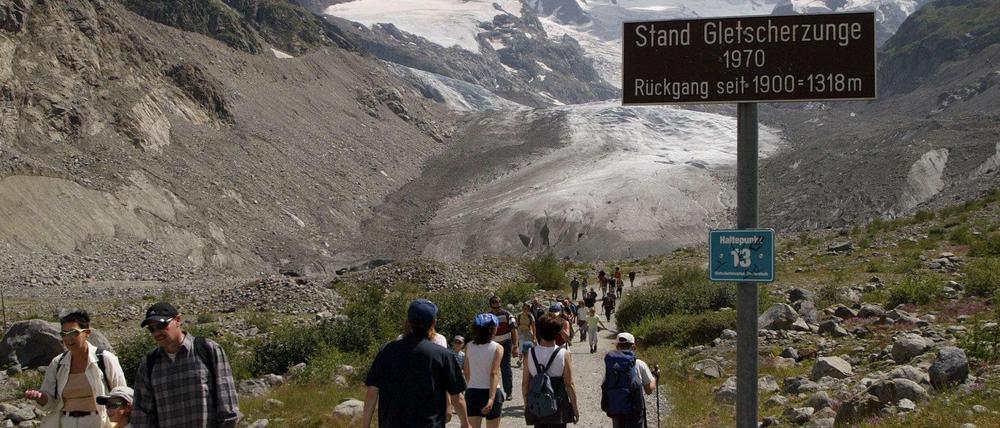Zahlreiche Wanderer pilgern zum Morteratschgletscher bei Pontresina im Oberengadin (Archivbild vom 22.07.2003) an einem Schild vorbei, dass den Stand der Gletscherzunge aus dem Jahr 1970 markiert. Auf der Suche nach Abkühlung spazieren sie von der Station Morteratsch zum Fuße des Morteratschgletschers im Berninagebiet. 