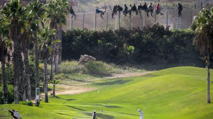 Afrikanische Flüchtlinge versuchen, einen Sperrzaun der spanischen Exklave Melilla zu überwinden - während auf dem Rasen Golf gespielt wird. Das Bild veröffentlichte eine lokale Flüchtlingshilfsorganisation.