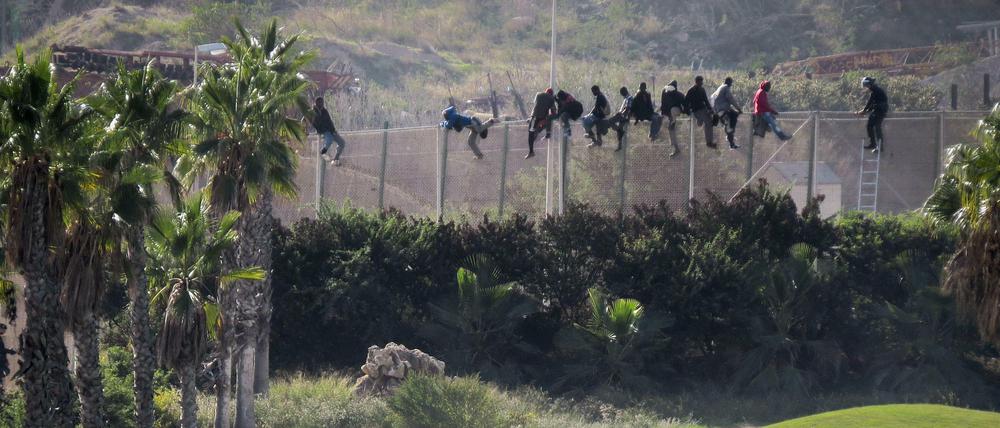 Afrikanische Flüchtlinge versuchen, einen Sperrzaun der spanischen Exklave Melilla zu überwinden - während auf dem Rasen Golf gespielt wird. Das Bild veröffentlichte eine lokale Flüchtlingshilfsorganisation.