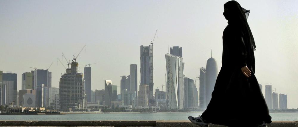 Eine Frau spaziert vor der Skyline der Stadt Doha (Katar). Mehrere arabische Golfstaaten und Ägypten haben die diplomatischen Beziehungen zu Katar abgebrochen. 