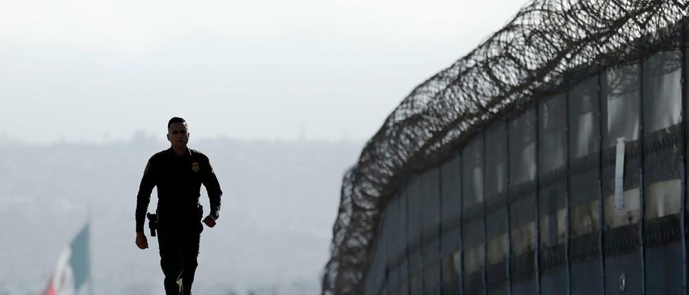 Der US-Grenzpolizist Eduardo Olmos läuft entlang des Zauns an der Grenze zwischen USA und Mexiko in San Diego (USA). 