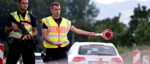 Polizisten kontrollieren Fahrzeuge, die aus Österreich nach Deutschland kommen.