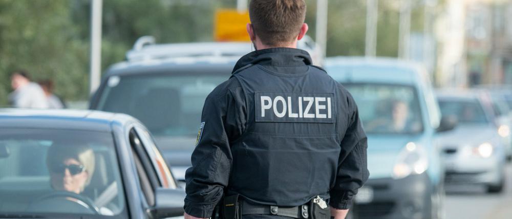 Ein Bundespolizist kontrolliert an der deutsch-österreichischen Grenze im bayerischen Simbach am Inn Fahrzeuge.