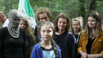 Greta Thunberg steht mit Aktivisten im Hambacher Forst, eine ist vermummt.