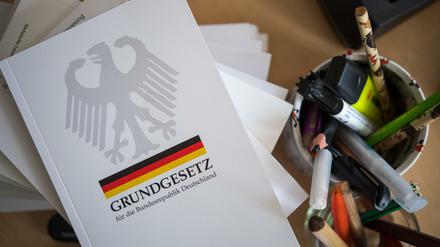 Eine Ausgabe des Grundgesetzes der Bundesrepublik Deutschland liegt auf einem Tisch neben Schreibutensilien.