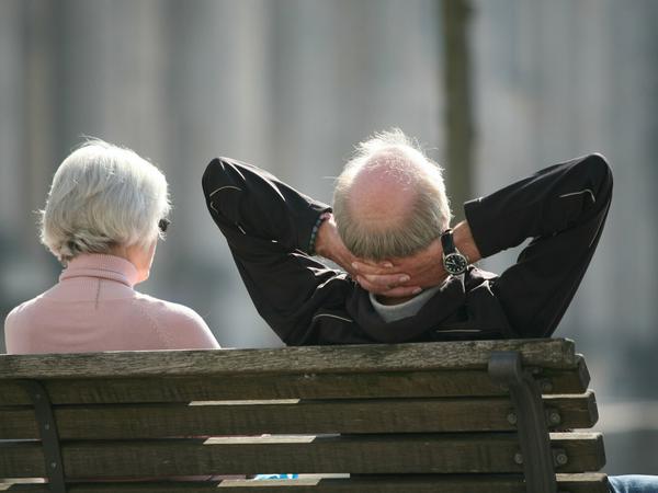  Ein Rentnerpaar sitzt auf einer Bank vor dem Reichstag und sonnt sich.