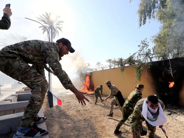Hashd al-Shaabi-Milizen entzünden eine Feuer auf der Mauer der US-Botschaft im Irak.