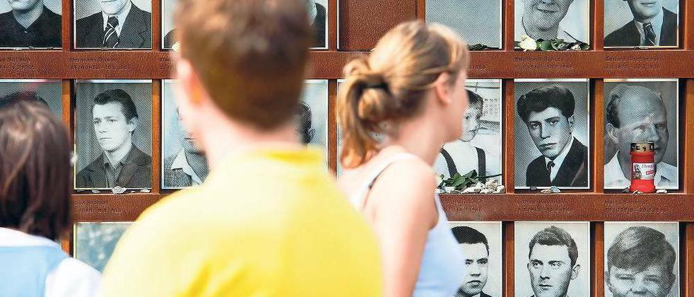 An der Gedenkstätte. Besucher sehen sich am 50. Jahrestag des Mauerbaus Fotos von Todesopfern an, die bei der Flucht von Ost nach West ums Leben kamen. Foto: Clemens Bilan/dapd