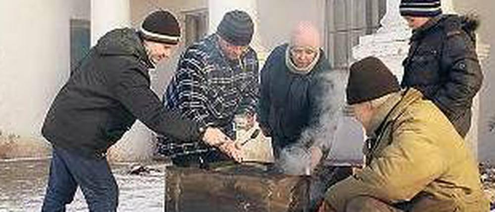 Am offenen Feuer kochen Bewohner der Stadt Mironowka. 