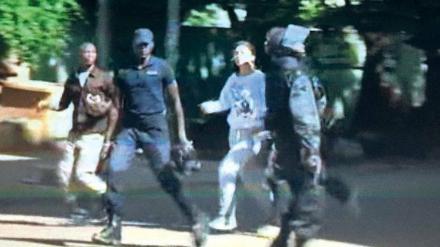 Bloß weg hier! Das von einem Bildschirm abfotografierte Foto eines Videos zeigt aus dem Hotel fliehende Geiseln, die von Sicherheitskräften begleitet werden. 