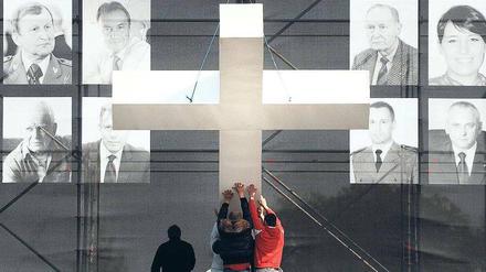 Gedenken. Vor Fotos der Absturzopfer wird in Warschau ein Kreuz aufgerichtet. Foto: AFP