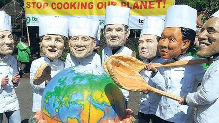 Petersberger Klimadialog. Demonstranten mit Masken der mächtigsten Politiker stehen vor einem Kochtopf, in dem symbolisch das Klima der Erde erhöht wird. Foto: dpa