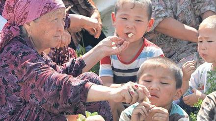 Selbsthilfe. Eine Frau verteilt Brot an Kinder – Szene aus einem Flüchtlingslager in Südkirgistan diese Woche.Foto: Maxim Shipenkov/epa
