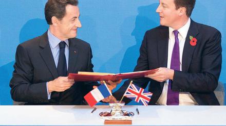 Sarkozy (l.) und Cameron machen aus der Finanznot eine militärische Tugend.