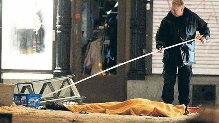 Tatort Stockholm. Ein Ermittler untersucht noch am Samstagabend einen der Anschlagsorte in der schwedischen Hauptstadt. Der Leichnam des getöteten Attentäters ist mit einer Plane abgedeckt. Am Sonntag waren hier wieder Passanten unterwegs. 