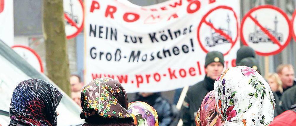 Gegen Moscheen marschieren Gruppen wie Pro Köln – hier beim Richtfest der Kölner Ditib-Moschee im Februar, beobachtet von türkischen Frauen. Was als fremd gilt und ausgegrenzt wird, kann sich jedoch ändern. Foto: Knippertz/dapd