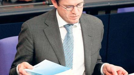 Karl-Theodor zu Guttenberg mit einem Exemplar seiner Doktorarbeit am 23. Februar im Bundestag. Die Uni Bayreuth bescheinigt ihm „defizitären Arbeitsstil“. Foto: dpa