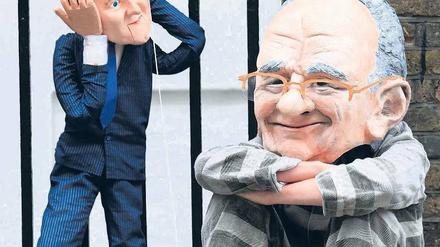 Ein Demonstrant macht vor der Londoner Wohnung von Rupert Murdoch dem Unmut über den Abhörskandal Luft – Murdoch wird dabei in Häftlingskleidung dargestellt, während der britische Premier David Cameron als Puppe agiert. Foto: Andrew Winning/Reuters