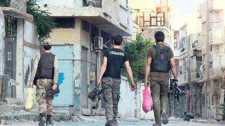 Im Kriegszustand. Mitglieder der syrischen Oppositionsarmee tragen Munition durch die Straßen der Stadt Homs. 