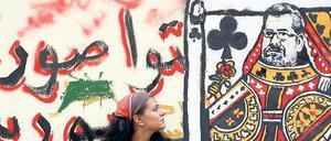 Im Spiel. Eine Frau schaut in der Innenstadt von Kairo auf ein Graffito, das den Präsidenten Mohamed Mursi als Spielkarte zeigt. 
