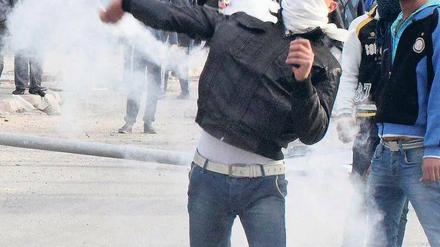 Ein Demonstrant schleudert einen Behälter mit Tränengas in Richtung Polizei. Foto: rtr