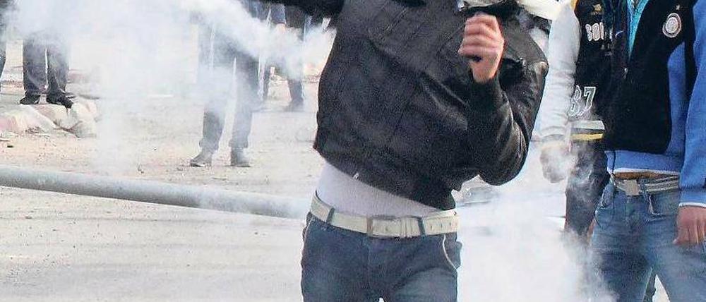 Ein Demonstrant schleudert einen Behälter mit Tränengas in Richtung Polizei. Foto: rtr