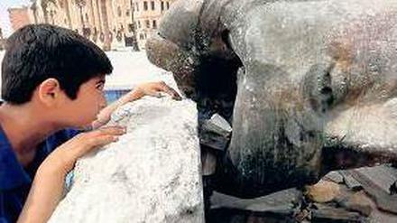 Ein Junge mit einer zerstörten Statue von Hafez al Assad, Vater von Baschar. Foto: Reuters