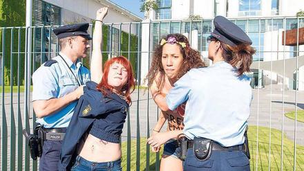 In Aktion. Polizisten bedecken vor dem Amtssitz der Kanzlerin die entblößten Oberkörper von zwei Femen-Aktivistinnen. Foto: Marcus Golejewski/Geisler-Fotopress