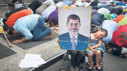 Gebet als Protest. Mehrere hundert Menschen demonstrieren in New York gegen das gewaltsame Vorgehen der Übergangsregierung in Kairo gegen die Muslimbruderschaft. Ein Kind hält dabei ein Plakat mit dem Konterfei des gestürzten Präsidenten Mohammed Mursi hoch.