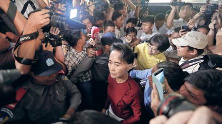 Lady in Red. Aung San Suu Kyi wird im Wahllokal von Medien umlagert.