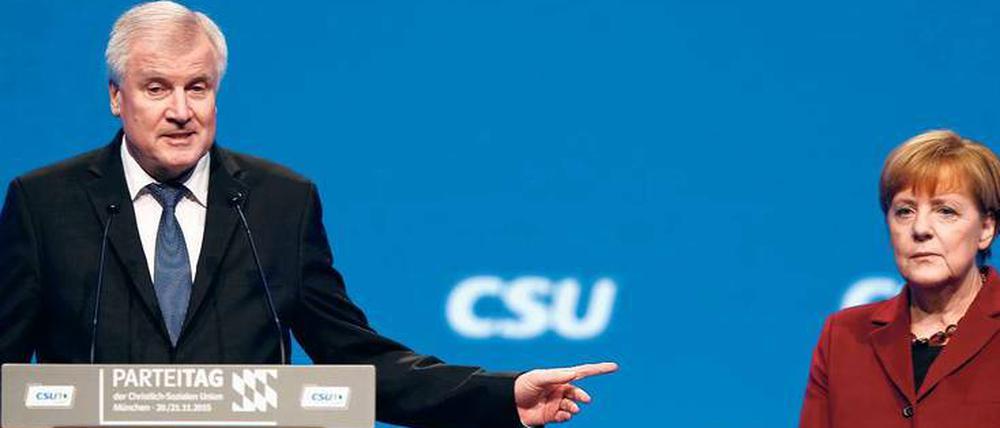 Wer gibt uns die Obergrenze nicht? Horst Seehofer beharrt auf seiner Position in der Flüchtlingsfrage, Angela Merkel steht regungslos daneben. 