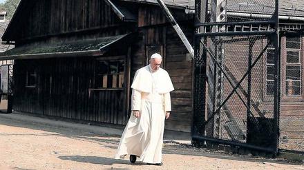 Papst Franziskus durchschreitet schweigend in der KZ-Gedenkstätte Auschwitz-Birkenau das Lagertor mit der zynischen Aufschrift „Arbeit macht frei“.