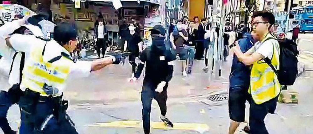 Ein Hongkonger Polizist zückt eine Pistole und schießt einem Demonstranten in den Bauch. Der 21-Jährige liegt schwer verletzt im Krankenhaus.
