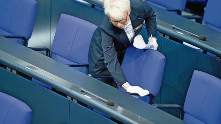 Eine Bundestagsmitarbeiterin desinfiziert in einer Pause die Regierungsbank.