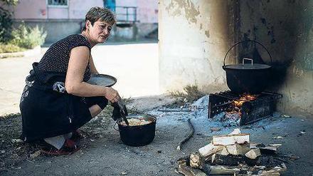 Die Lebensbedingungen werden immer härter. Eine Frau muss vor der Tür über offenem Feuer kochen.
