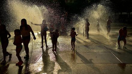 Spanien, Pamplona: Menschen kühlen sich in einem Brunnen ab, als die Sonne an einem heißen Sommertag untergeht.