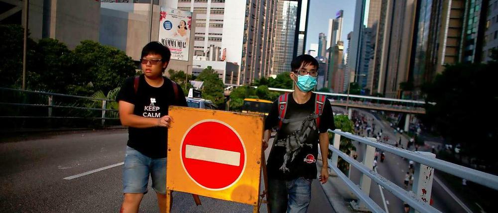 Zwei Demonstranten in der Nähe des Regierungsviertels in Hongkong tragen ein Straßenschild.
