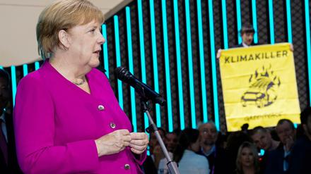 Kanzlerin Angela Merkel (CDU) bei der Internationales Automobilausstellung in Frankfurt - und eine Aktivistin von Greenpeace auf einem Auto.