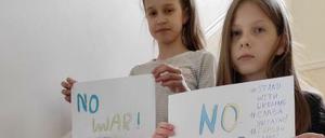Kinder einer Kiewer Familie halten im Treppenhaus "No War"-Schilder in die Kamera.